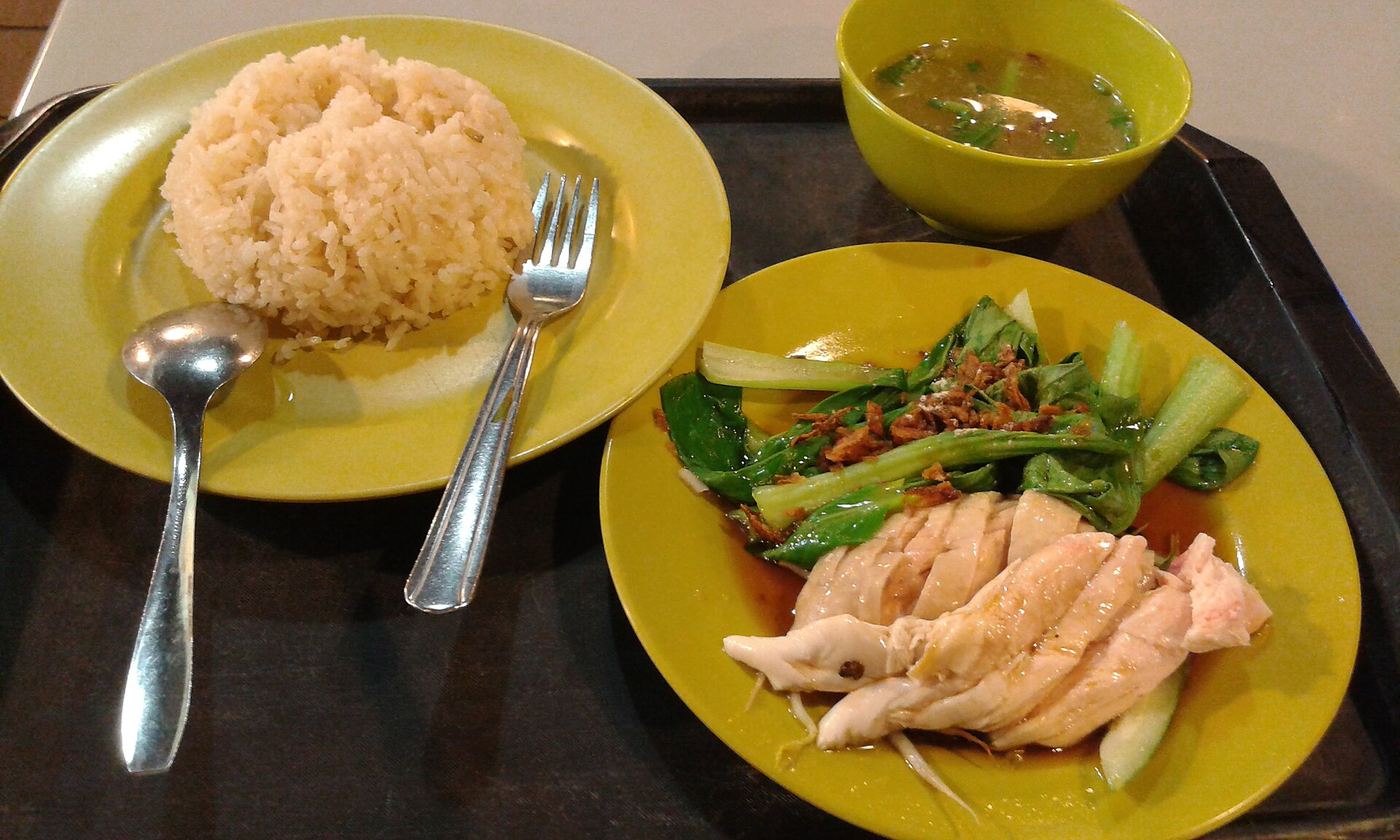 Hainanese chicken rice on a plate, with cucumber and chilli.