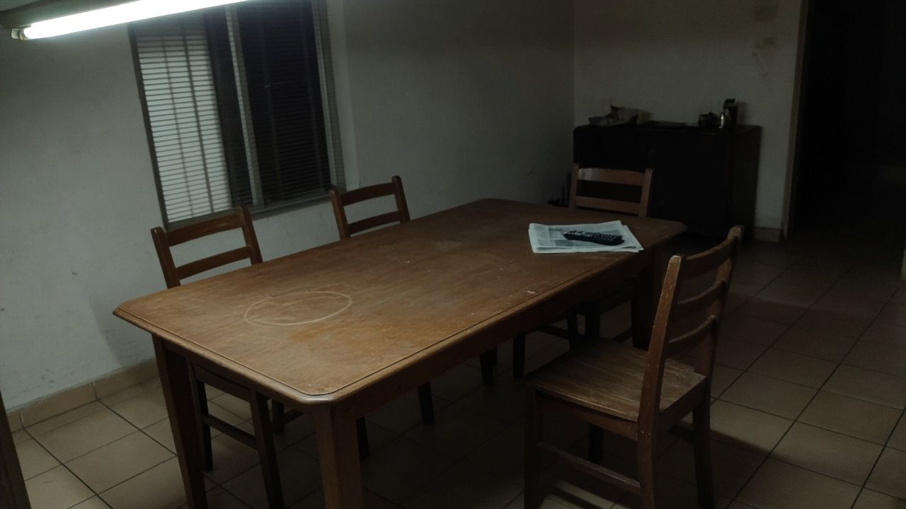 An empty wooden dining table in a flat at night.